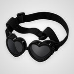 Black heart-shaped goggles with dark lenses and an adjustable elastic strap, shown on a light gray background.