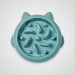 A teal-colored silicone cat slow feeder bowl with ear-like protrusions and internal textured ridges, shown from a top-down view on a light gray background.