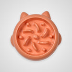 An orange cat puzzle feeder bowl with cat ears on the rim, shown from a top-down view on a light gray background.