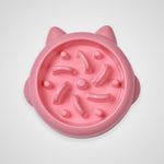 A pink silicone cat slow feeder bowl with ear-like protrusions and internal textured noodle channels, shown from a top-down view on a light gray background.