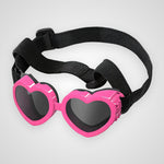 Pink heart-shaped children's sunglasses with dark lenses and an adjustable black elastic strap, shown on a light gray background.
