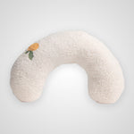 A U-shaped, fluffy white textured pillow with a small embroidered orange flower and green leaves on the left side, set against a light gray background.