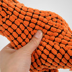 A close-up of a textured orange and brown woven fabric or towel being held by a hand to show its thick, raised nodule pattern.