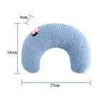 A light blue U-shaped memory foam neck pillow with a textured sherpa-like surface, featuring a small pink cartoon character accent on the upper left curve. The image includes dimension lines and text indicating measurements of 27cm width, 16cm height, and 6cm depth on a solid white background.