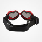 Heart-shaped goggles with red frames and mirrored silver lenses, featuring a wide black elastic strap with a plastic buckle, shown on a light gray background.