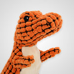 An orange textured plush dinosaur toy with a cream-colored belly and a small black bead eye, shown against a light gray background.