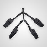 A black four-point harness with adjustable straps and padded shoulder and hip pouches, laid flat on a light gray background.